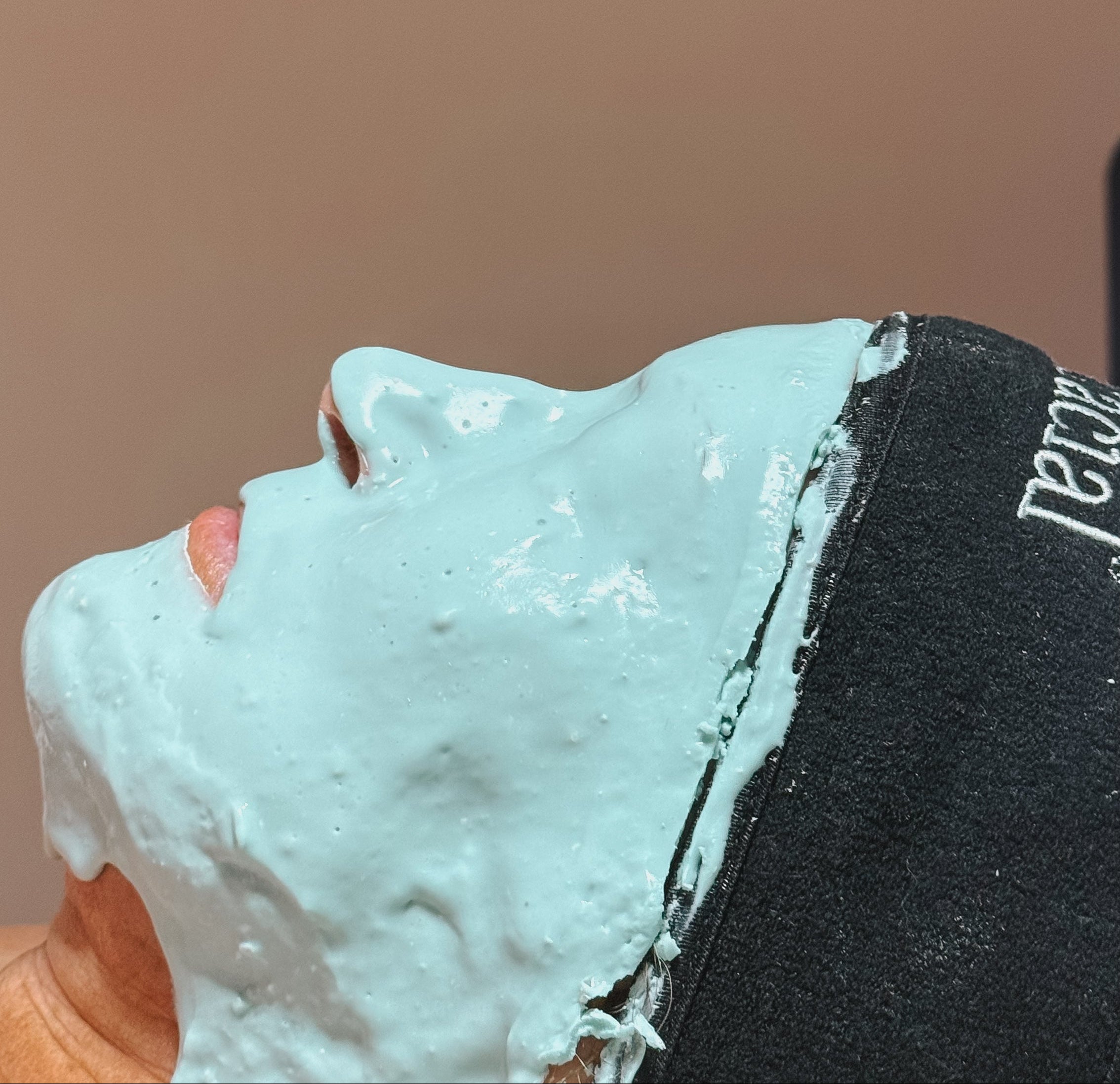 Person applying a blue facial mask with a blurred background
