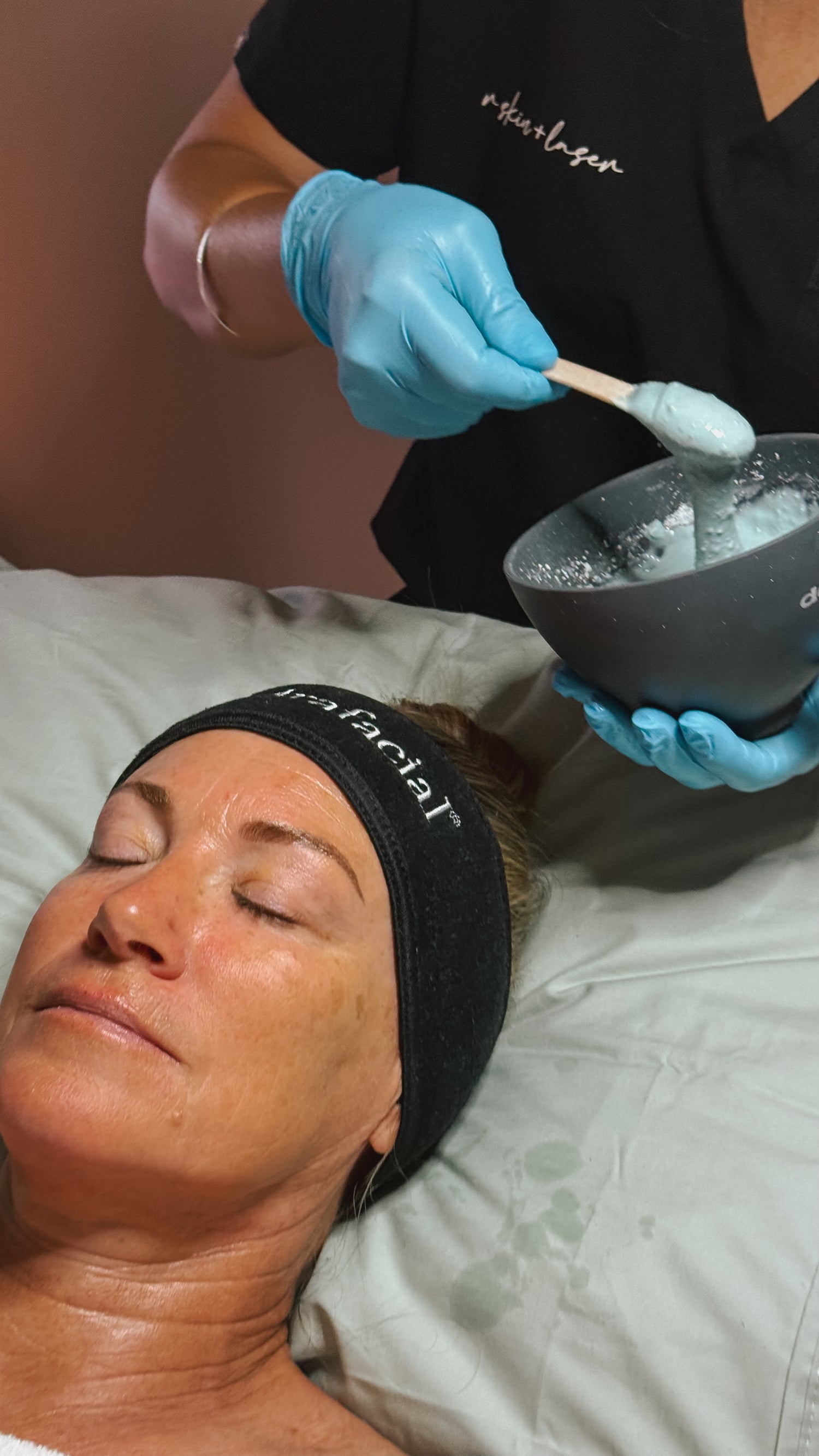 Person receiving a facial treatment with a professional in a spa setting.