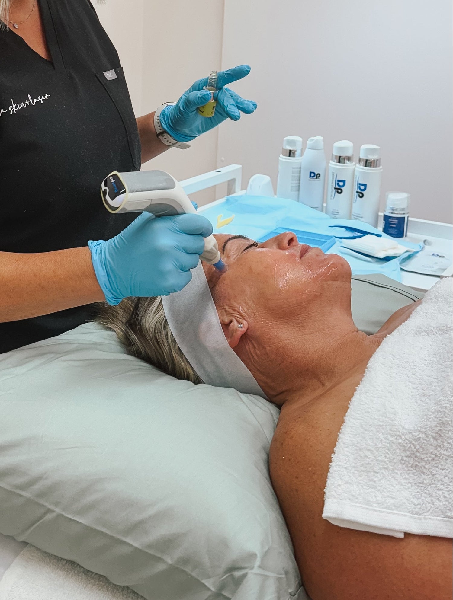 Facial skin needling procedure in a clinical setting with a technician and client.